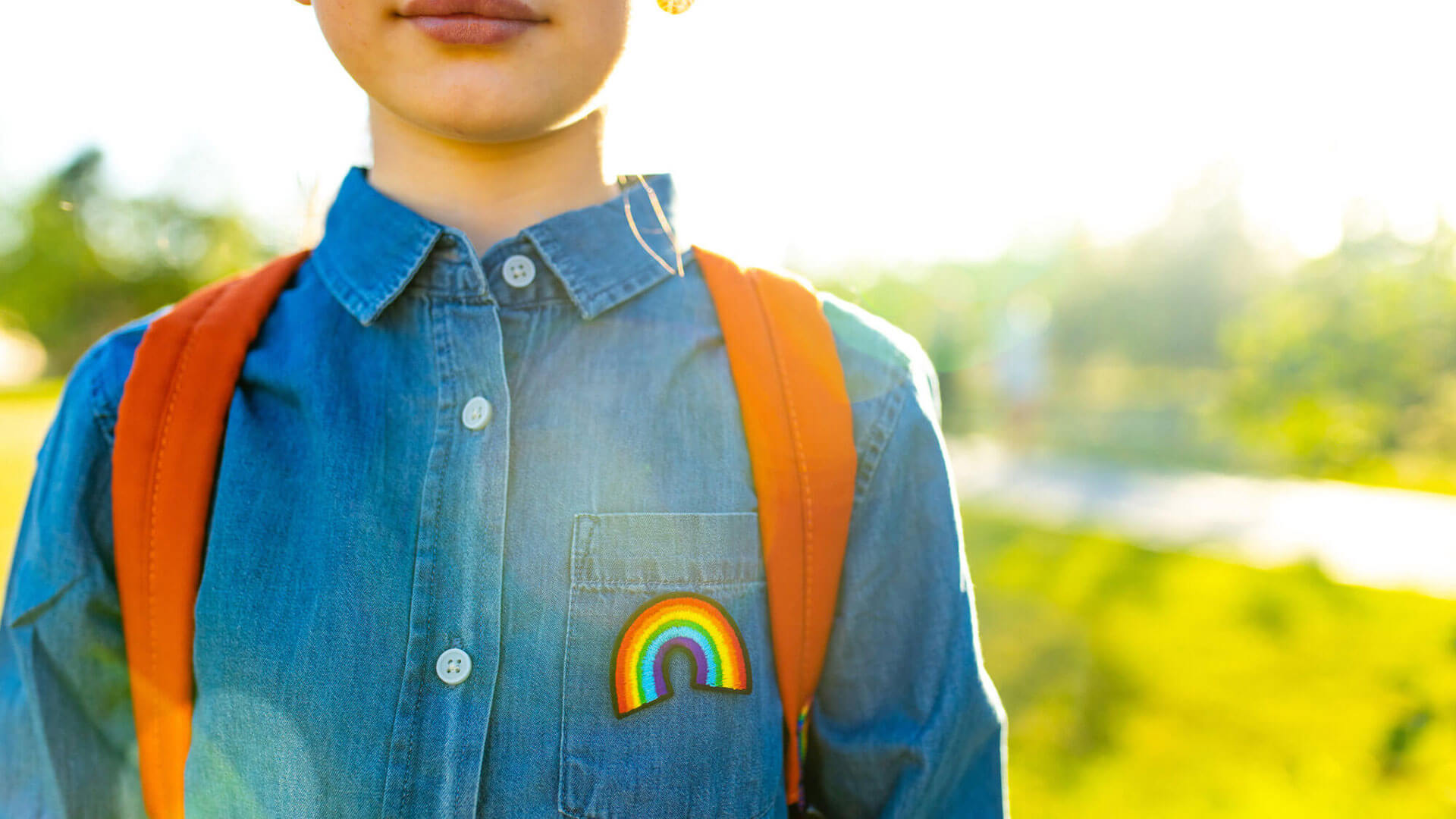 close-up photo of a child wearing a rainbow patch and a backpack
