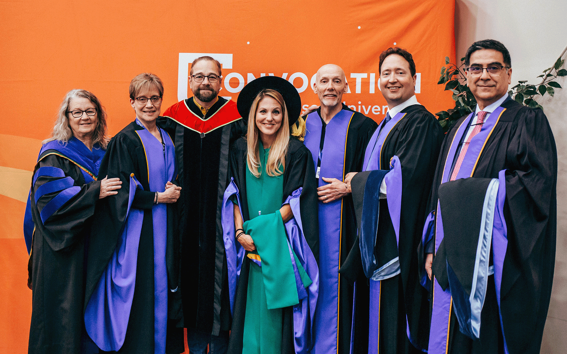 Group of people dressed in academic regalia smiling at the camera