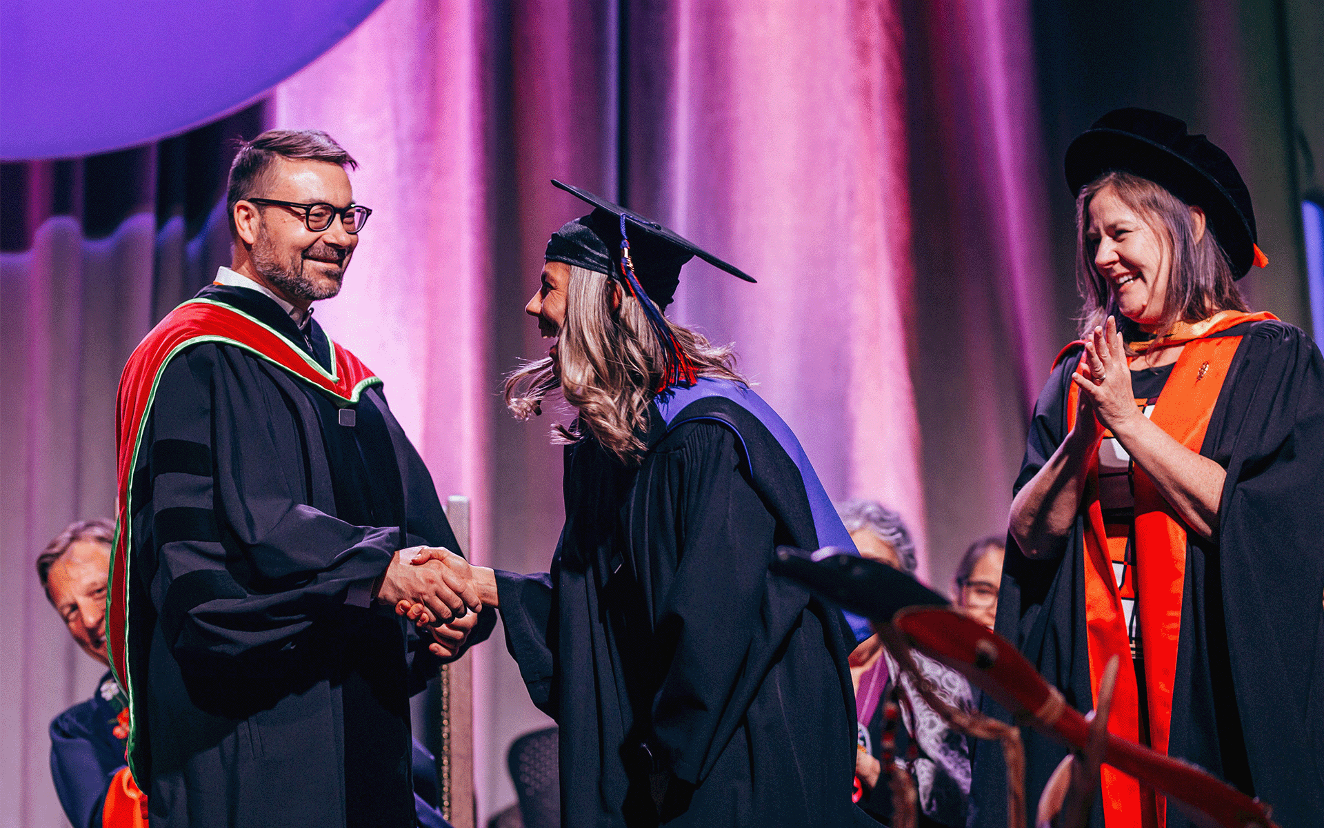 Graduate shaking hands with a dean during the convocation ceremony