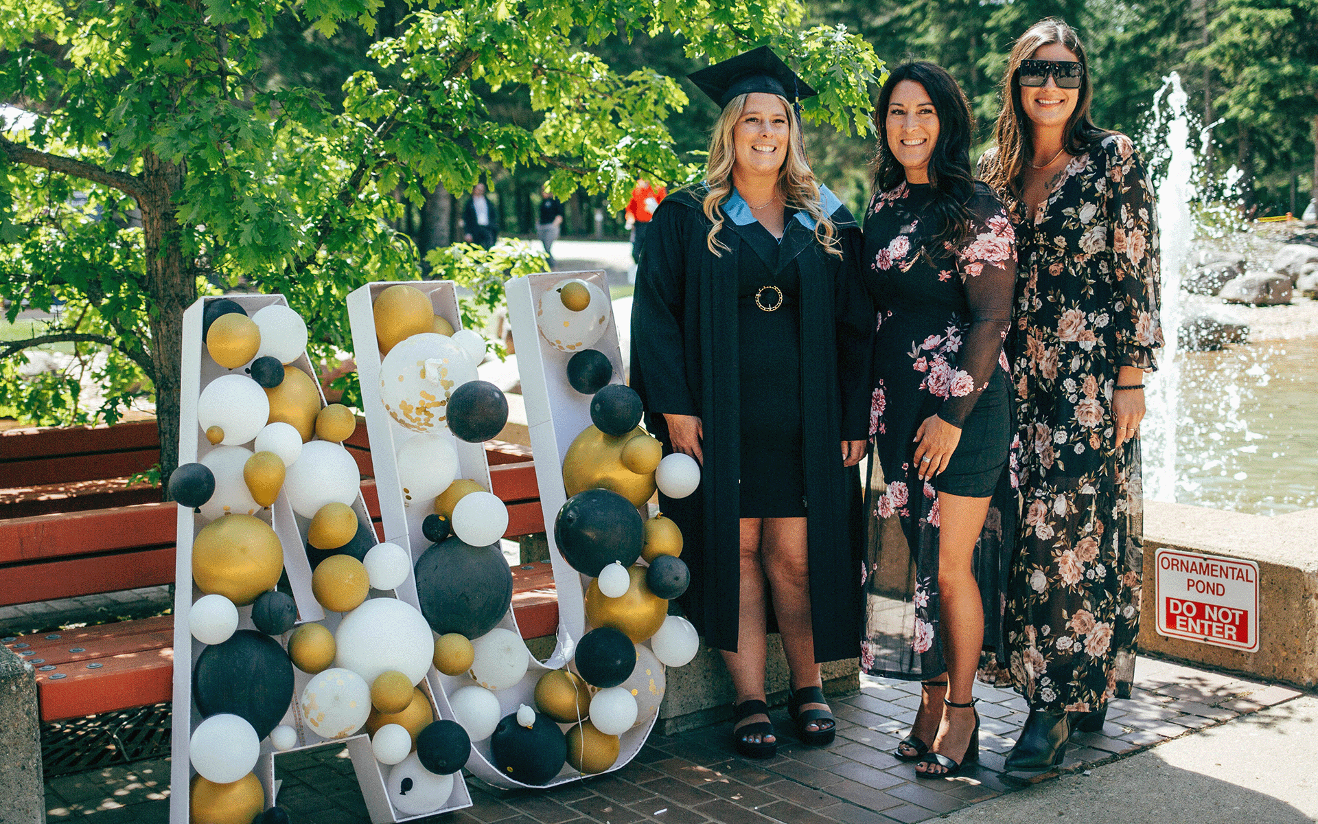 a grad and her two family members posing for a photo next to a balloon AU sign