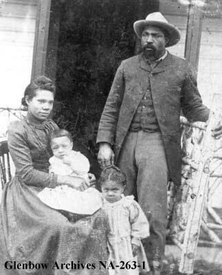 John Ware standing beside his wife and two children.