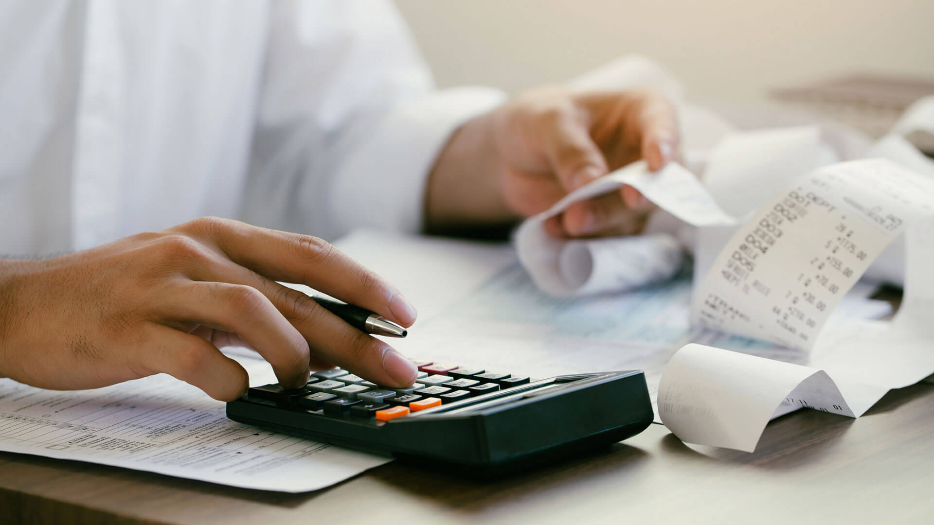 person using calculator to add up receipts