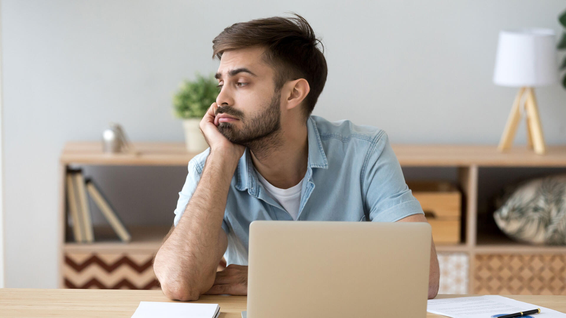 a person looking bored in front of their laptop