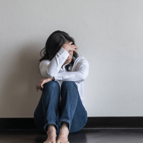 person sitting on floor with their head in their hands