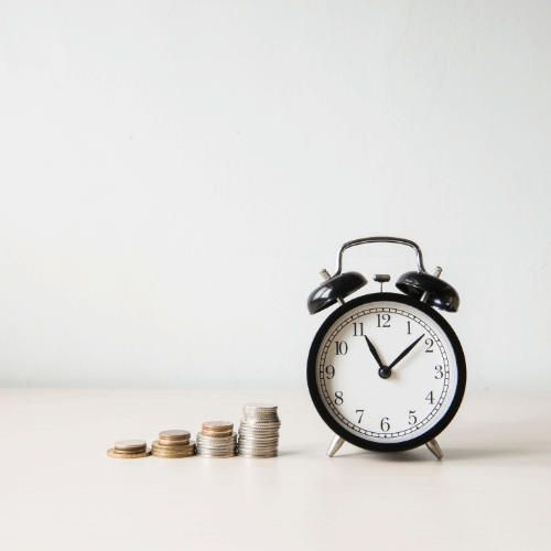 alarm clock with coins stacked up beside it