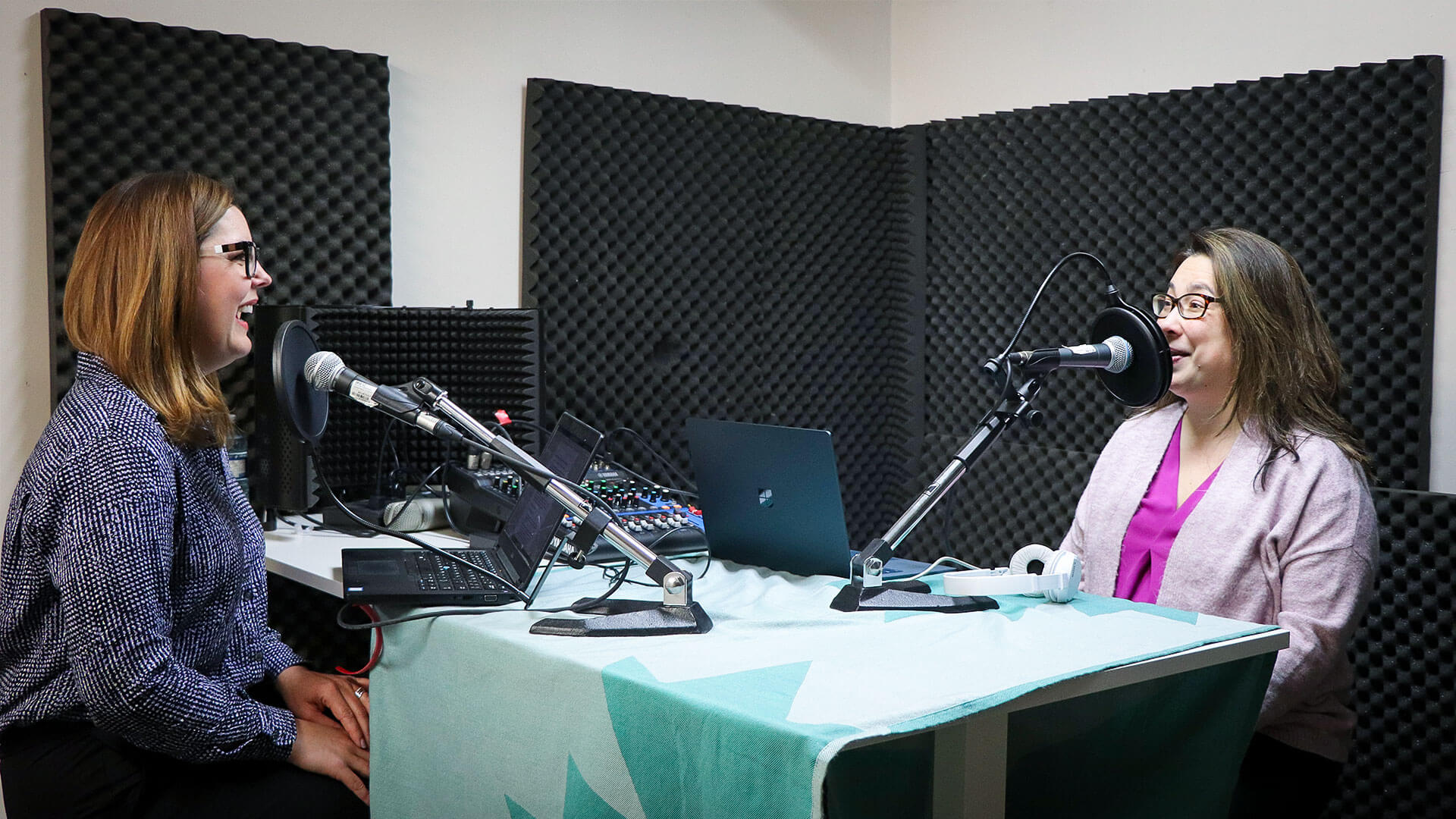 two women at a podcast recording in front of microphones