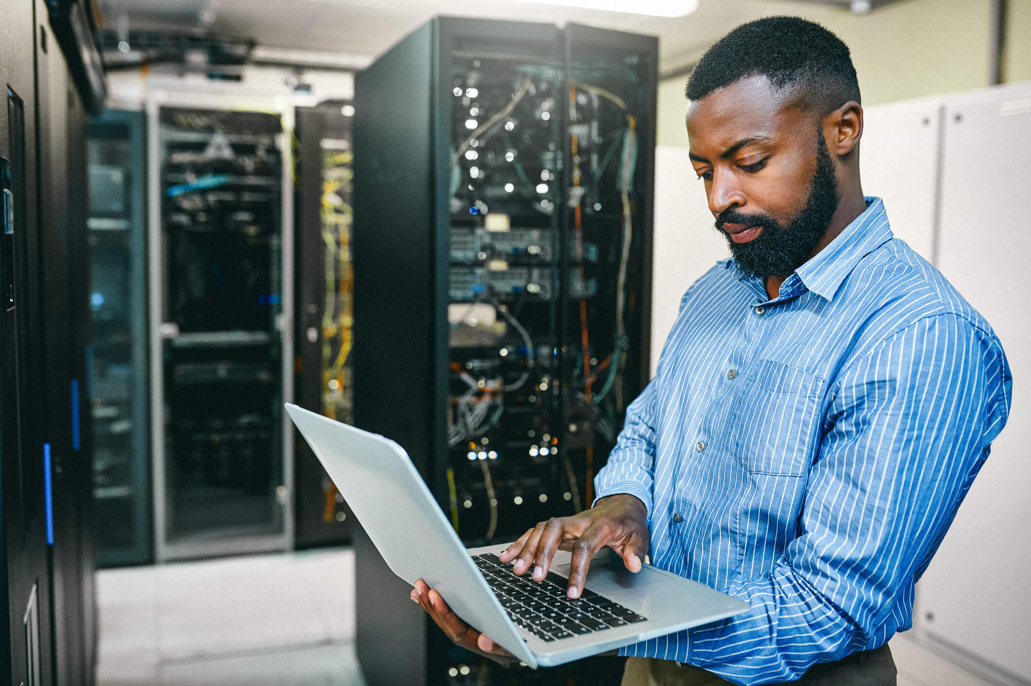 Shot of a young man using a laptop while working in a server room