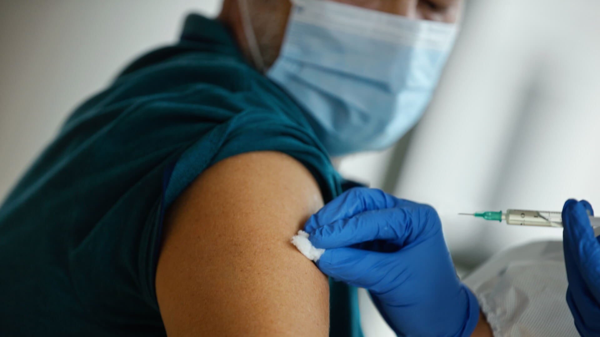 a patient receives an injection from a health-care worker in the upper arm.