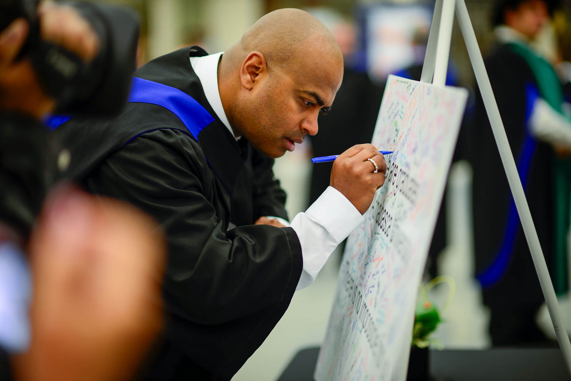 An AU graduate signs a poster