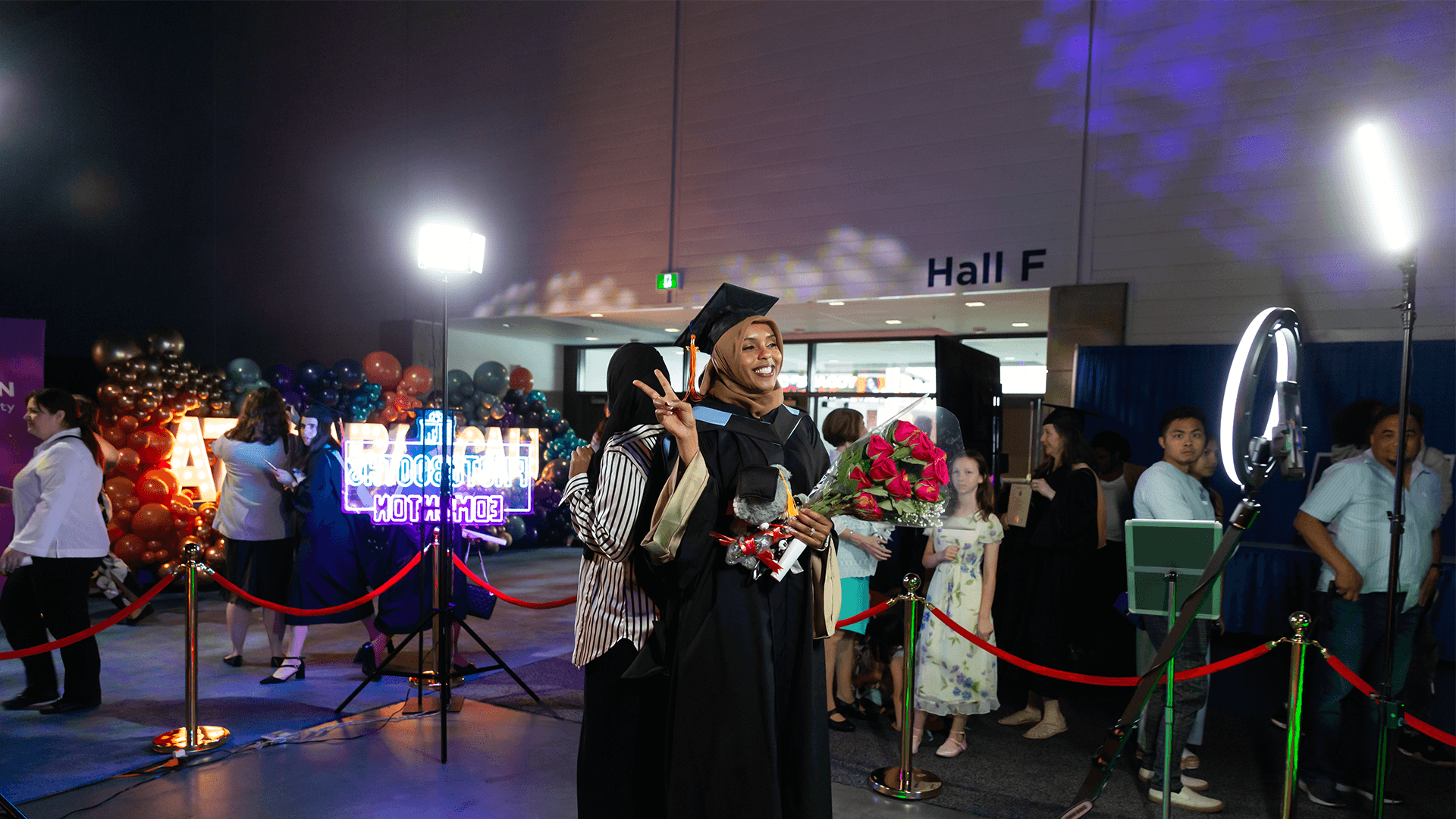 image of grad doing the peace sign holding roses and smiling for a photo