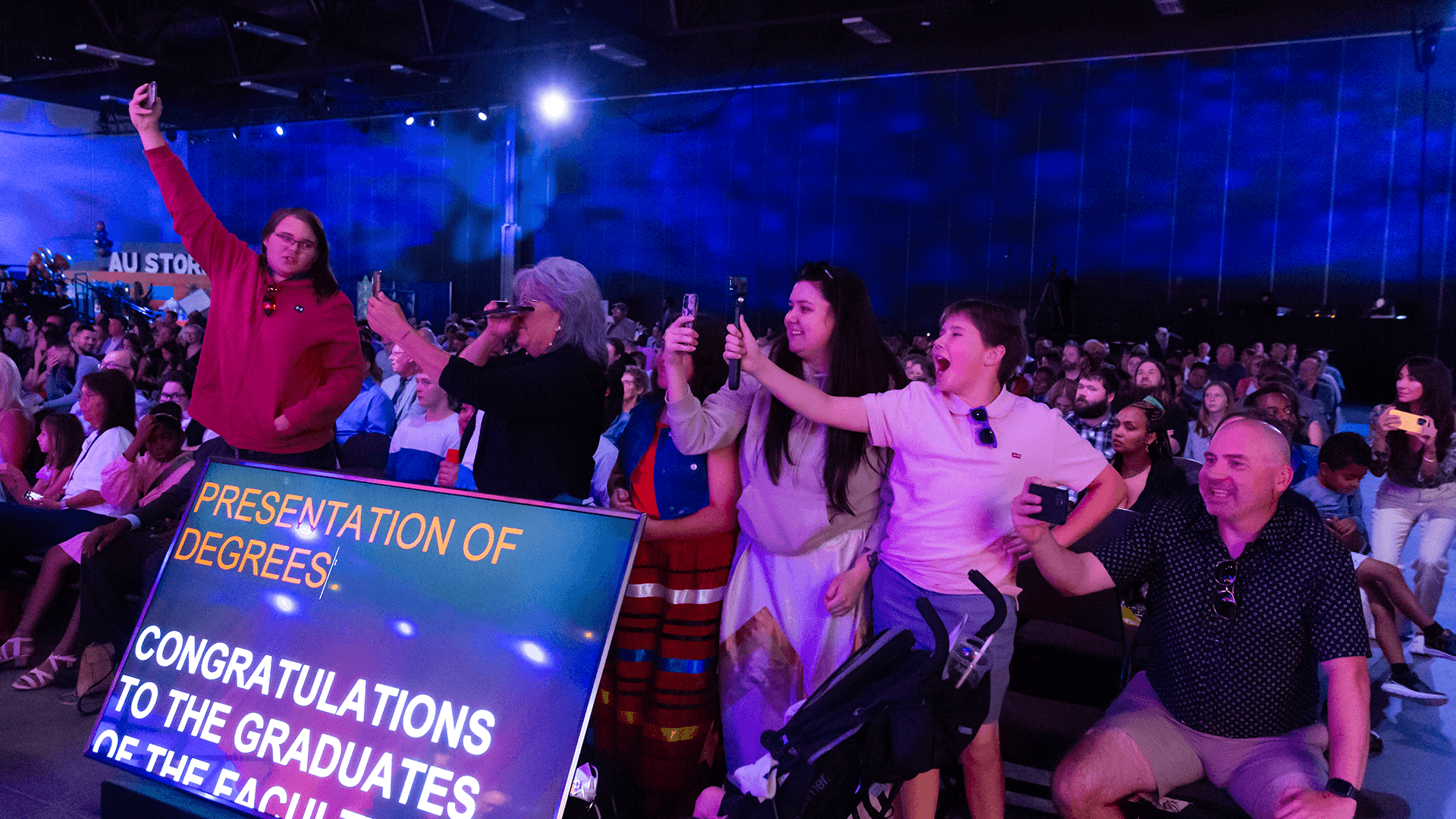 audience shot of excited attendees holding up their phones and taking pictures