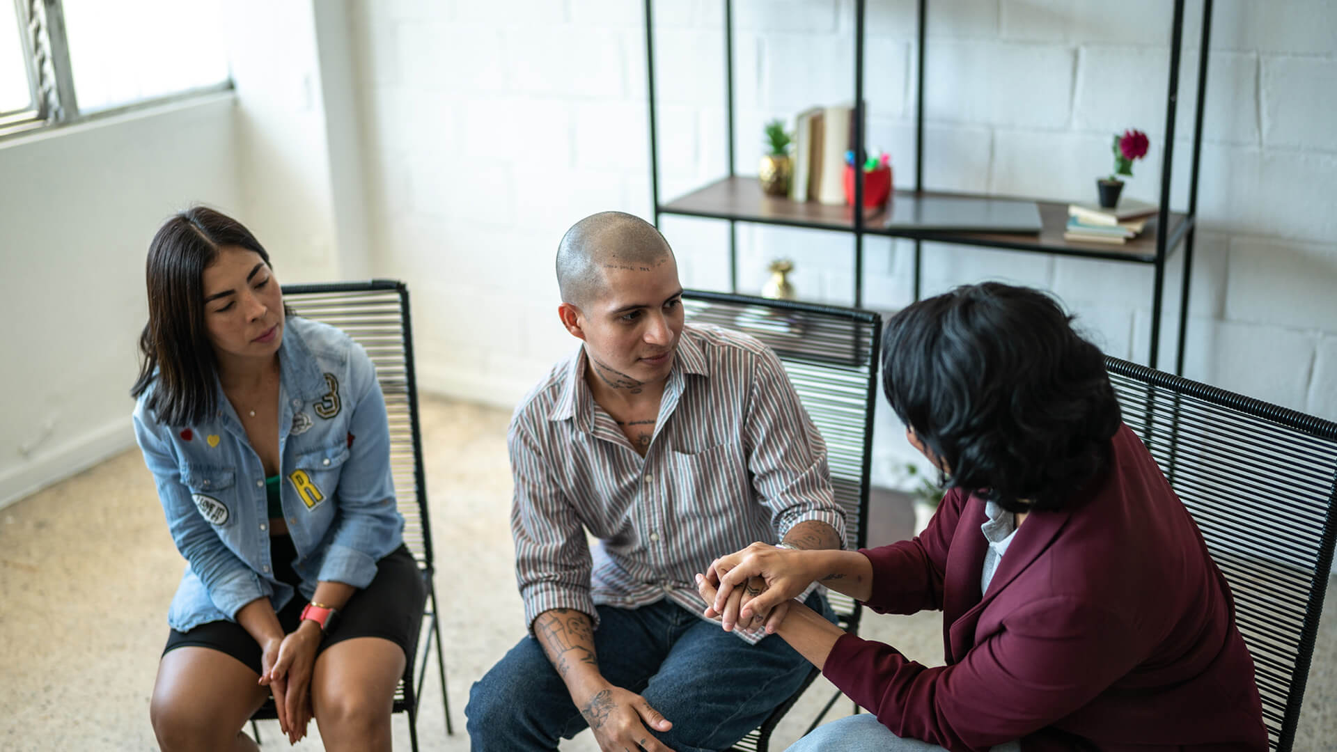 Two young people chat with a therapist in a bright room