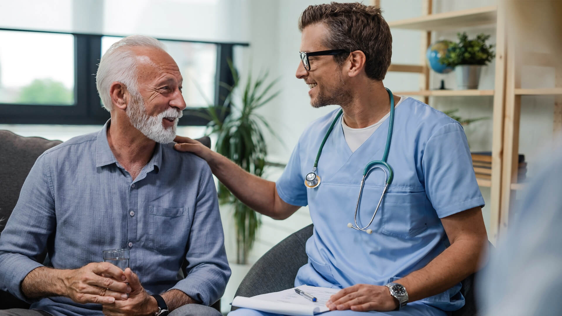 Male nurse re-assuring an older patient and smiling