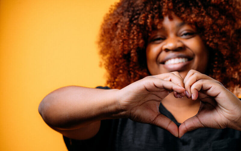 Black woman making a heart shape with her hands