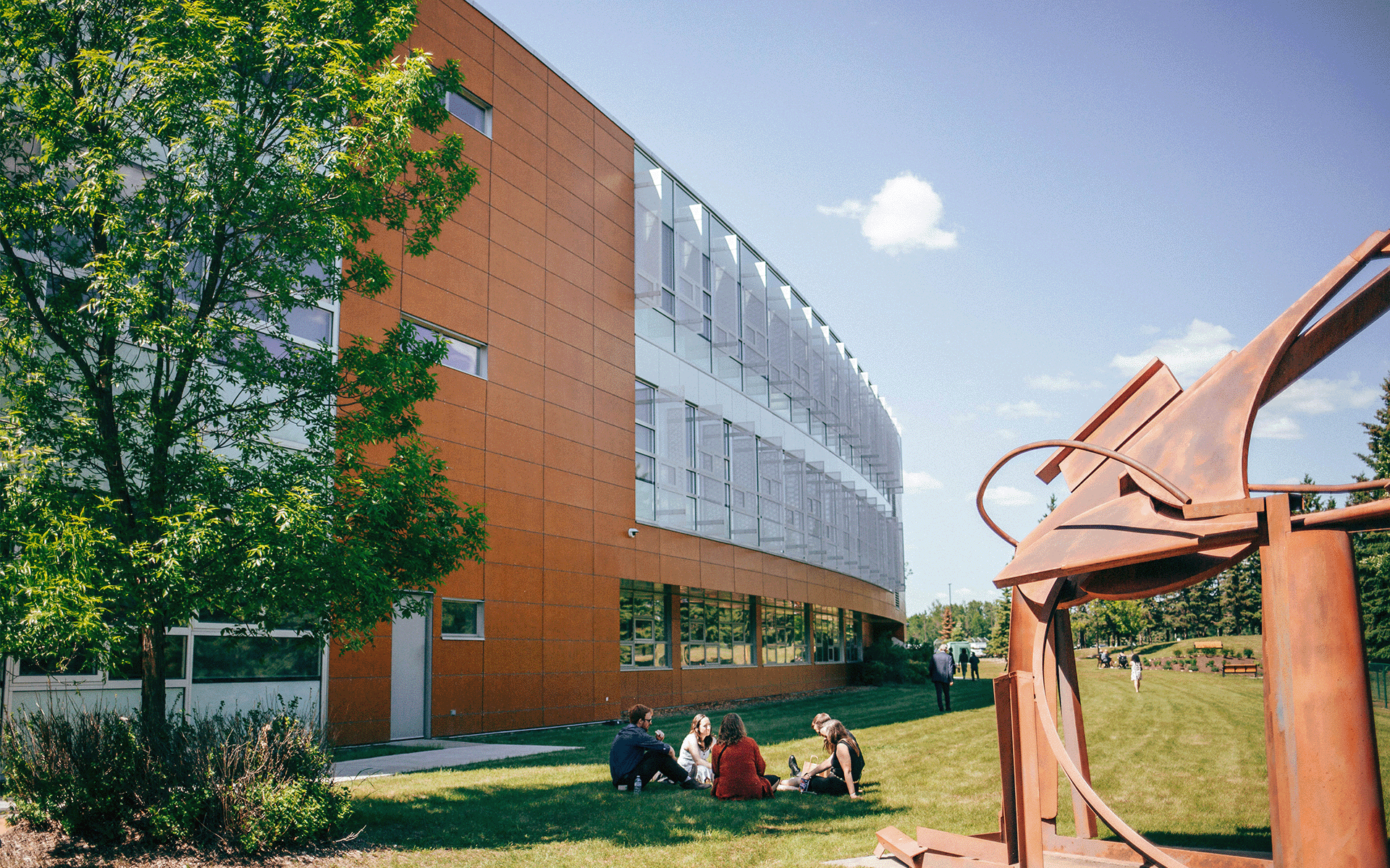 people sitting on the AU campus ground with the ARC building in the background