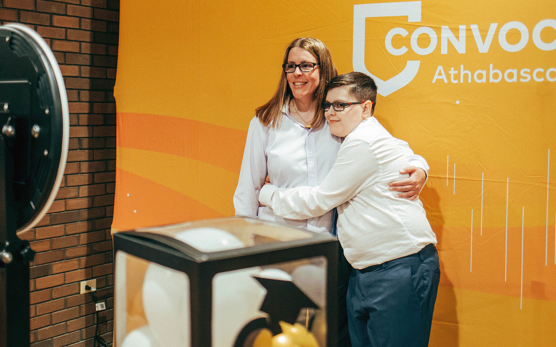 woman and kid taking a photo in front of a convocation banner