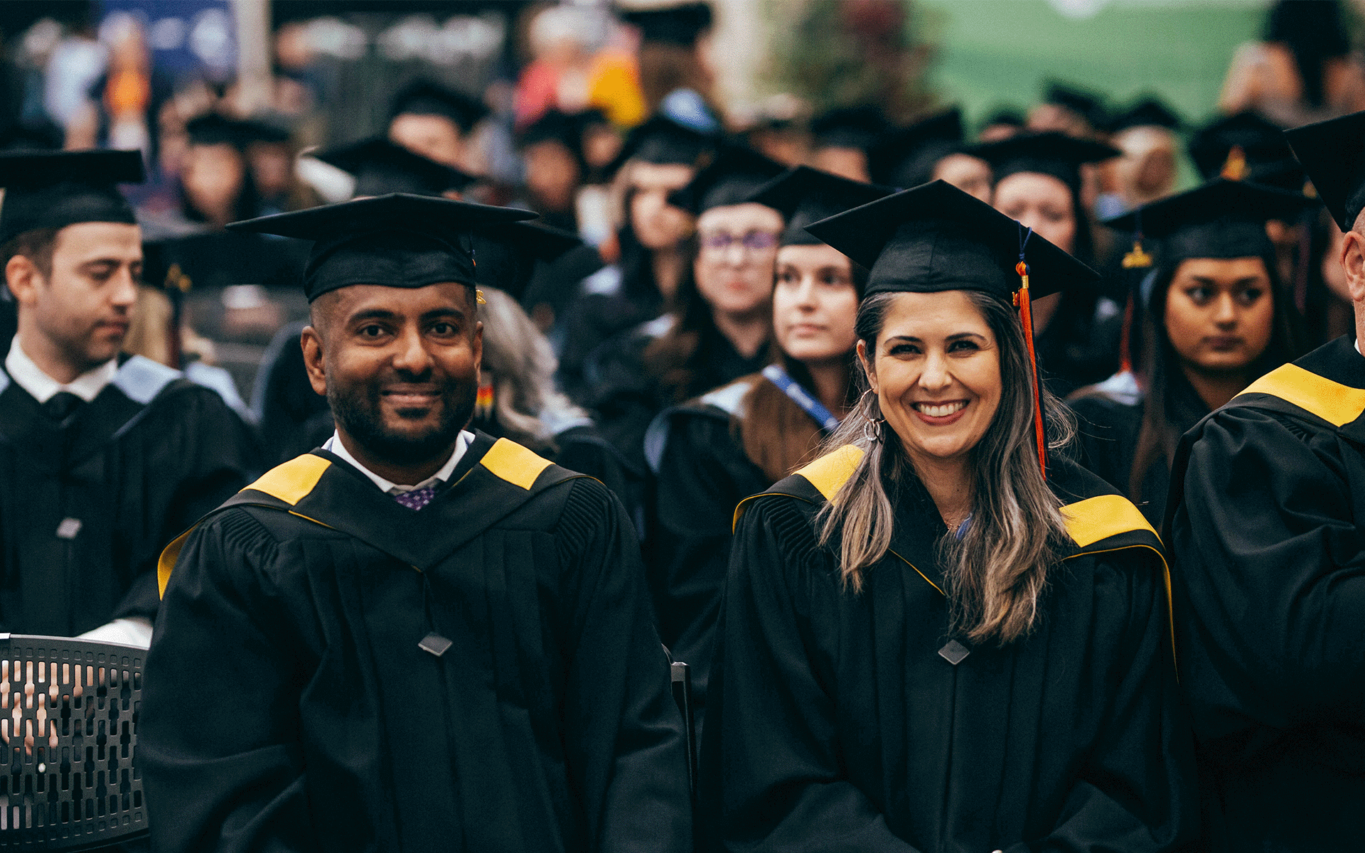 two graduates sitting next to each other and smiling at Athabasca University convocation