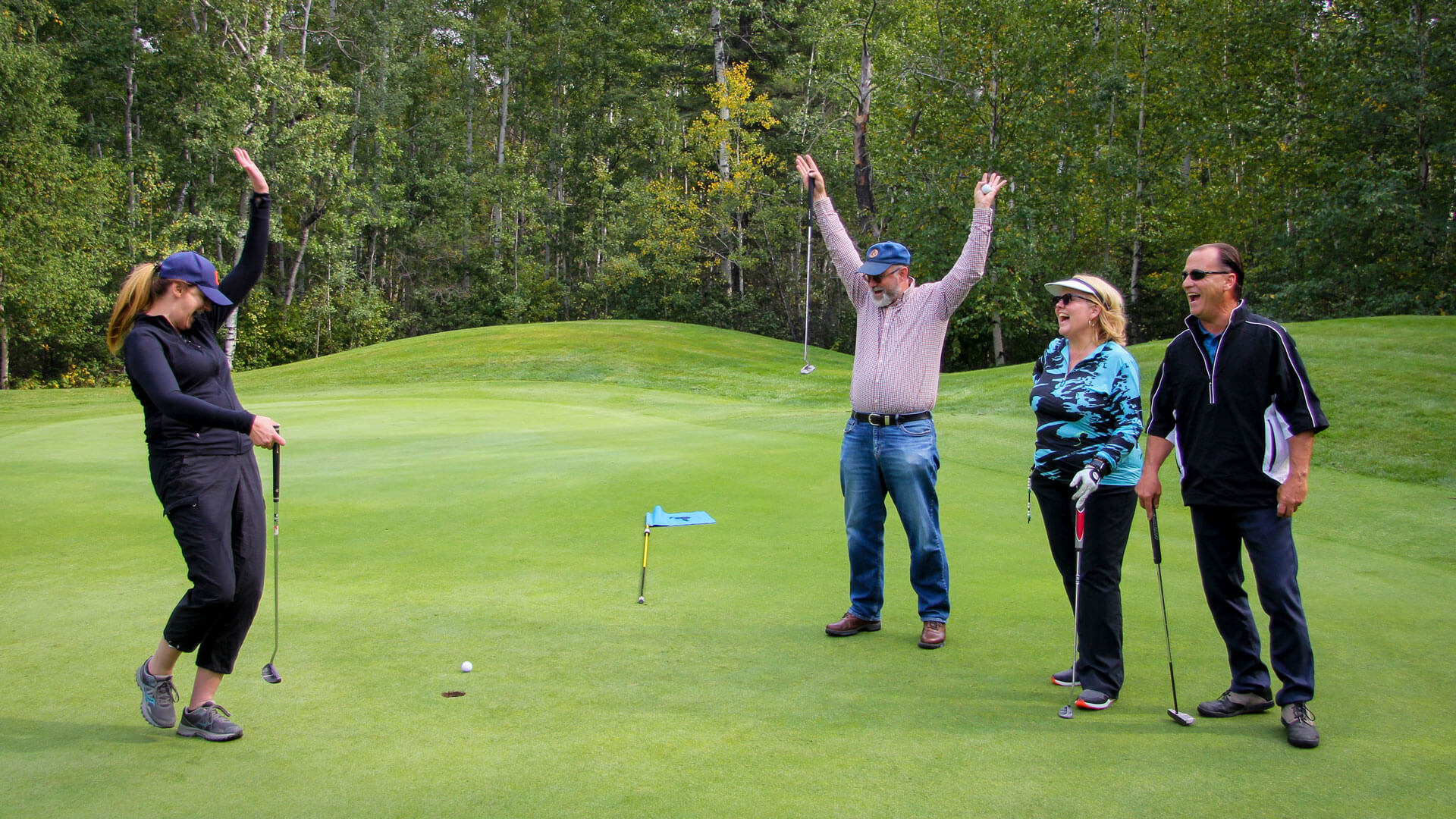 A group celebrates a putt at the Athabasca University golf tournament